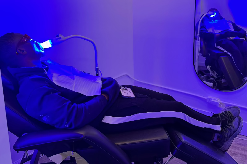 Person lying down in a Grin & Glow futuristic chair with blue lighting
