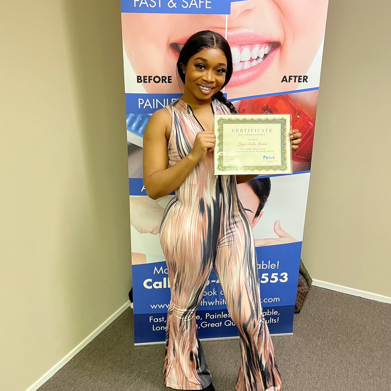Joyce Erika Parker holding her teeth whitening certification, showcasing professionalism and expertise as the founder of Grin and Glow.
