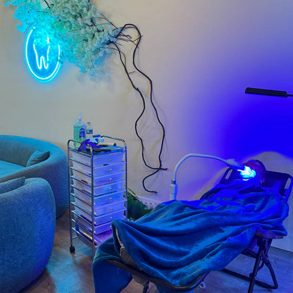 Modern luxury teeth whitening studio in Rochester featuring a blue neon tooth sign and comfortable client lounge.