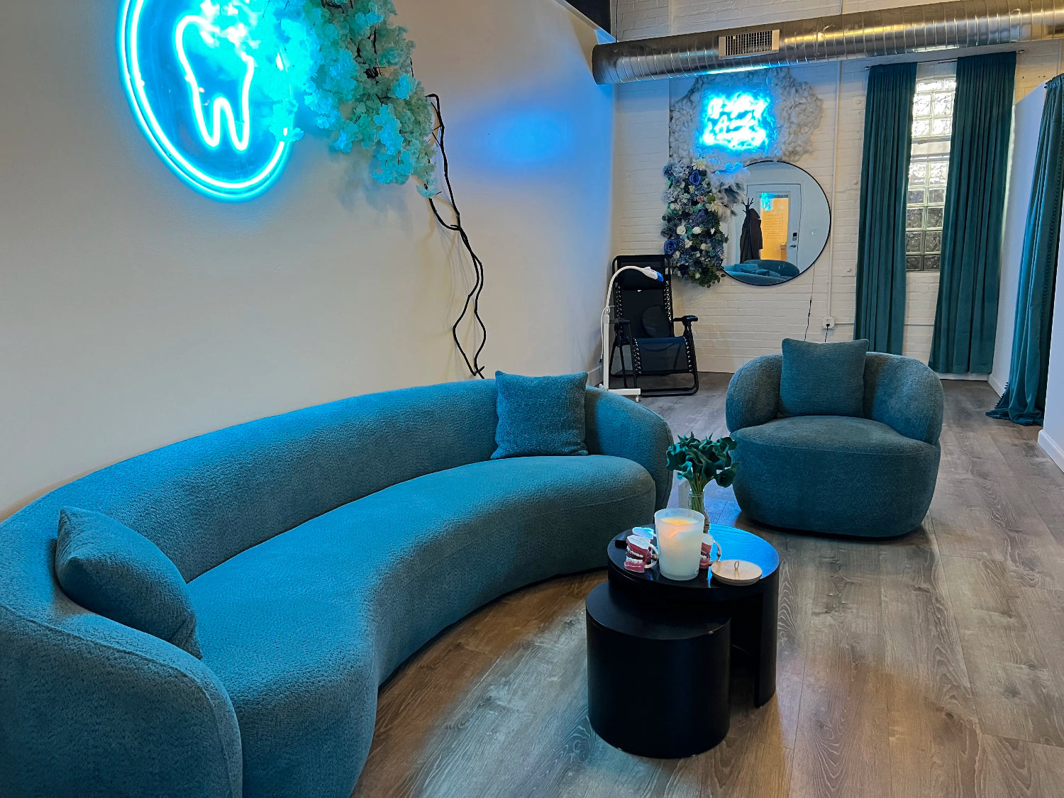 Private, luxury teeth whitening suites at Grin & Glow in Rochester featuring teal velvet curtains, modern orb lighting, and professional treatment beds.
